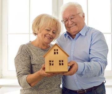 Elderly couple smiling holding birdhouse