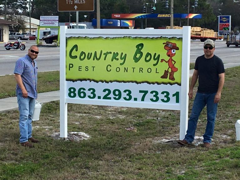 two employees standing near a Country Boy Pest Control sign